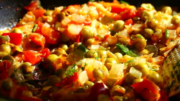 In a frying pan, fry from onions and carrots. Add green peas and frozen red peppers to the frying pan. — Stock Video