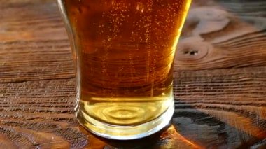 Bira cam cam içine dökülür. Sarı renk hafif, düşük-alkol içecek. Güzel kabarcıklar gazlı bir içecek. Bir bardak köpüklü bira bir retro masa üstü üzerinde.
