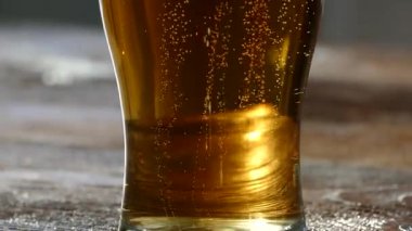 Bira cam cam içine dökülür. Sarı renk hafif, düşük-alkol içecek. Güzel kabarcıklar gazlı bir içecek. Bir bardak köpüklü bira bir retro masa üstü üzerinde.