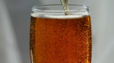 Bira cam cam içine dökülür. Sarı renk hafif, düşük-alkol içecek. Güzel kabarcıklar gazlı bir içecek. Bir bardak köpüklü bira bir retro masa üstü üzerinde.