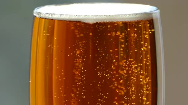 Beer is poured into a glass glass. Light, low-alcohol beverage of yellow color. Beautiful bubbles of a carbonated drink. A glass of foam beer on a retro table top.