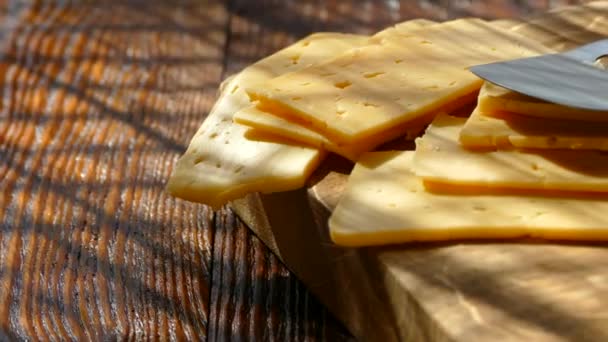 Il formaggio affettato e un coltello per formaggio si trovano su un tagliere . — Video Stock