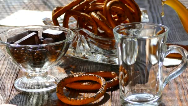 Na mesa, despeje o chá em uma xícara. Para o chá, uma sobremesa de doces de chocolate e bagels com sementes de papoula é servida. . — Vídeo de Stock