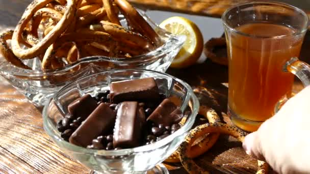 在桌子上, 把茶倒进杯子里。为茶, 甜点巧克力糖果和百吉饼与罂粟籽被提供. — 图库视频影像