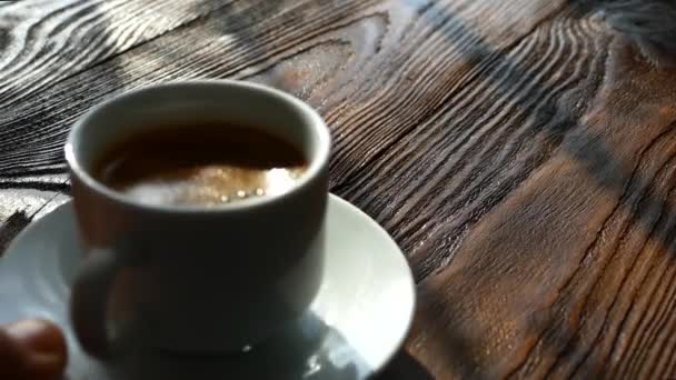 コーヒーのカップは、レトロなテーブルの上に置かれました。朝コーヒーのカップとソーサー。木製の茶色の背景. — ストック動画