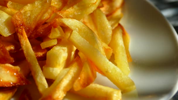 Les frites sont frites dans une poêle. Les pommes de terre sont frites dans une huile de tournesol. Une pomme de terre dorée et apétitique avec du ketchup à la tomate est mangée à la main . — Video