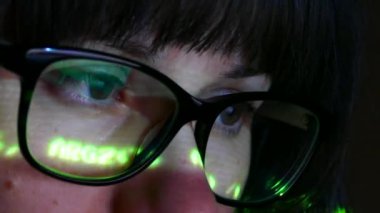 Bir kız ya da kadın bilgisayar ekranında gözlük takıyor. Karanlık bir odada internete göz atın..