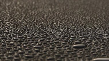 Siyah bir yüzeyde güzel su damlaları. Suyun yoğunluğu karanlık bir düzlemde toplandı. Çiğ tanesinin yansıması.