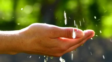 Su damlaları elde toplanır. Bir dağ çeşmesinden su iç. Çevre dostu su. Güneşin arka planına düşer.