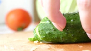 Mutfaktaki kesme tahtasında salatalık kesen kadın eller. Vejetaryen sağlıklı yiyecekler.