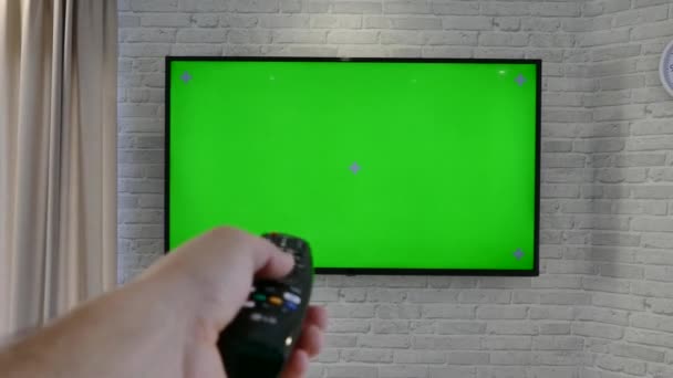 Un televisor de pantalla verde cuelga en la pared de la sala de estar. Sobre el fondo de una pared de ladrillo . — Vídeos de Stock