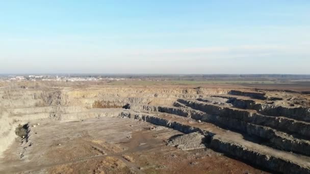 Gránitbánya. Gránitbányászati vállalkozás. A kilátás a kőfejtő magasságából. Egy kotrógép követ pakol egy teherautóba.. — Stock videók