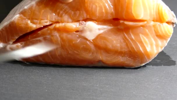 Κόψτε και ξεφλουδίστε φιλέτο σολομού σε ένα ξύλο κοπής. Αλάτι στο φιλέτο ψαριού. Μαγειρέψτε ένα πιάτο ψάρι στην κουζίνα. — Αρχείο Βίντεο