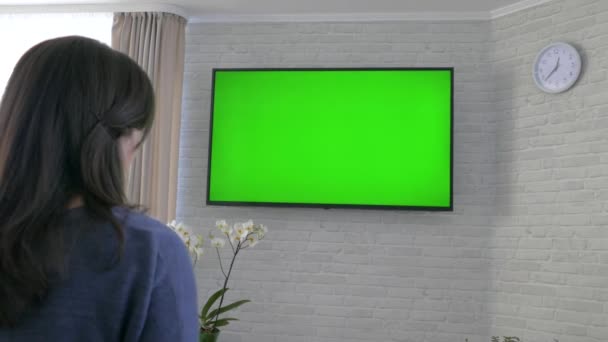 手里拿着遥控器看电视 客厅里靠墙的绿色荧幕电视 换频道 坐在家里休息 — 图库视频影像