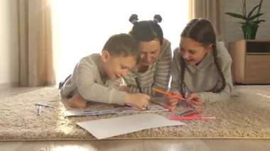 Evde mutlu bir aile. Kız ve erkek. Çocuklu annem paspasın üzerinde yatıyor. Keçeli kalem ve kalemlerle çizmek için. Küçük kız ve oğlu..