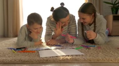 Evde mutlu bir aile. Kız ve erkek. Çocuklu annem paspasın üzerinde yatıyor. Keçeli kalem ve kalemlerle çizmek için. Küçük kız ve oğlu..