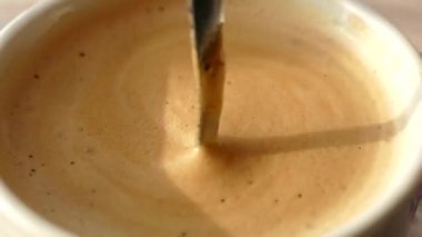 Waffle 'lı sabah kahvesi. Köpüklü bir içeceği kaşıkla bardağa koy. Sütlü ve köpüklü kahve..