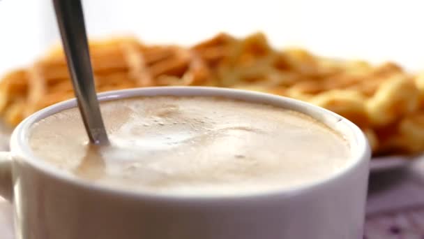 Café de la mañana con gofres. Golpea una bebida espumosa en una taza con una cuchara. Café con leche y espuma . — Vídeos de Stock