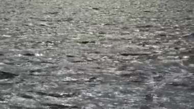 Su yüzeyindeki dalgalar. Gri dalga arka plan dokusu. Suyun üzerindeki güneş ışınlarının bir yansıması. Deniz nehri gölü.
