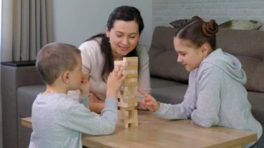 Çocuklu annem Jenga oyunu oynuyor. Mutlu bir aile evde birlikte zaman geçirir. Kız oğlan, erkek kardeş ve kız kardeş.