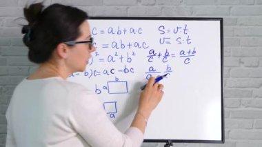 Bir öğretmen beyaz tahtaya işaretli formüller yazar. Evde öğreniyorum. Karantina sırasında uzaklık öğrenme.