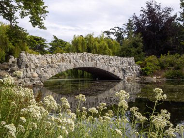 Doğa ile çevrili güzel bir parkta bir nehir üzerinde Güzel Taş duvar köprüsü