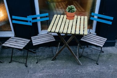 üç ahşap sandalye ve çiçekli bir kafe pencere yanındaki sokakta bir tablo