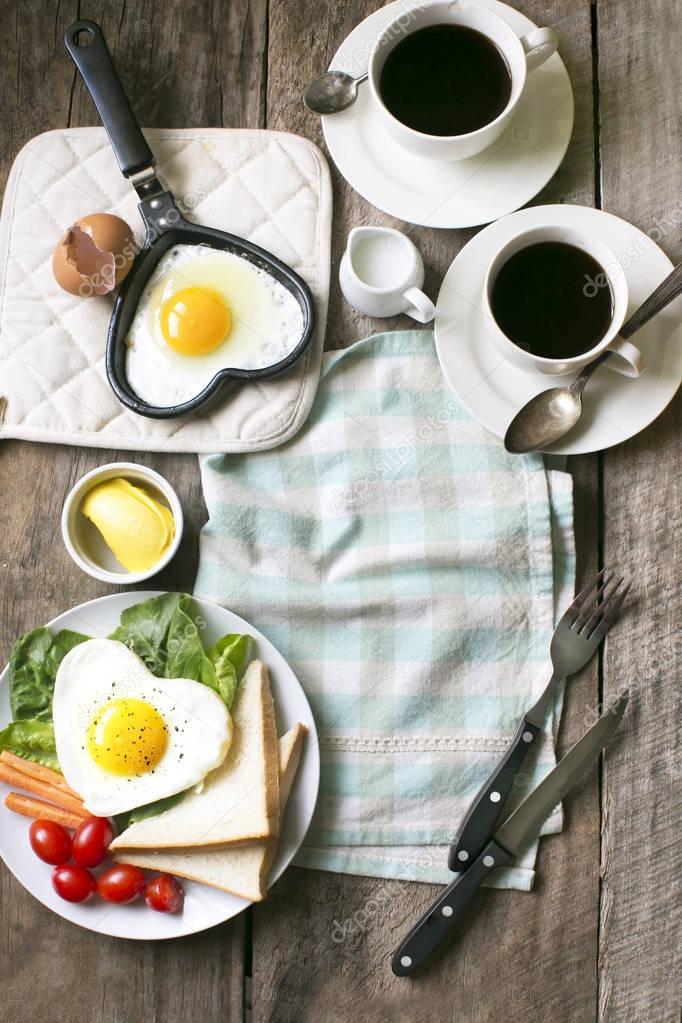 Flat lay heart shape healthy eating sunny side up english breakfast on wooden counter top.