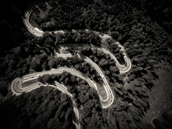 Carros na estrada sinuosa através da vista aérea da floresta — Fotografia de Stock