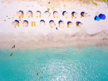Summer beach in Lefkada Greece with sun umbrellas and sunbeds an clipart