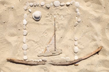Çakıl taşları ile sahilde sanatsal kum çizimler ve