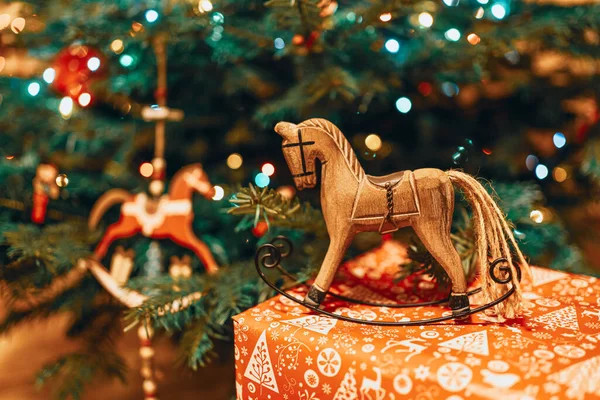 Christmas hobbyhorse made of wood on a present near a Christmas tree