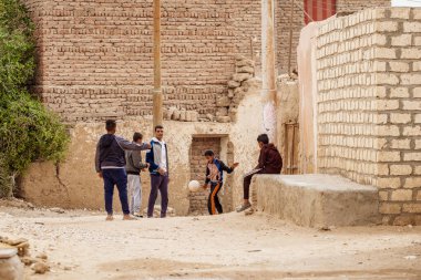 Luxor, Egypt - Jan. 2019: Daily life in Luxor, Egypt with boys playing football in the streets of the Luxor outskirts clipart