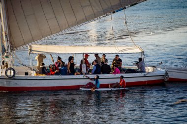 Aswan, Mısır - Aralık 2018: İki Mısırlı çocuk, Nil Nehri 'nin ortasında, turistlerin dikkatini çekmek için teknelerine doğru ilerliyorlar.