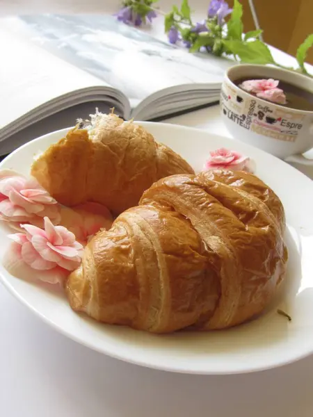 Croissants franceses em uma chapa com flores — Fotografia de Stock