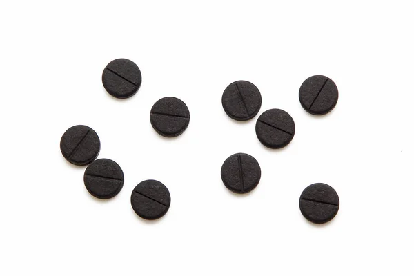 Чорні таблетки на білому тлі — стокове фото