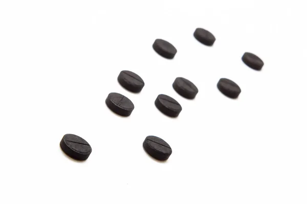 Чорні таблетки на білому тлі — стокове фото