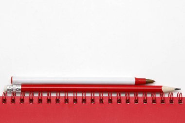 Beyaz arkaplanda kalem olan kırmızı defter