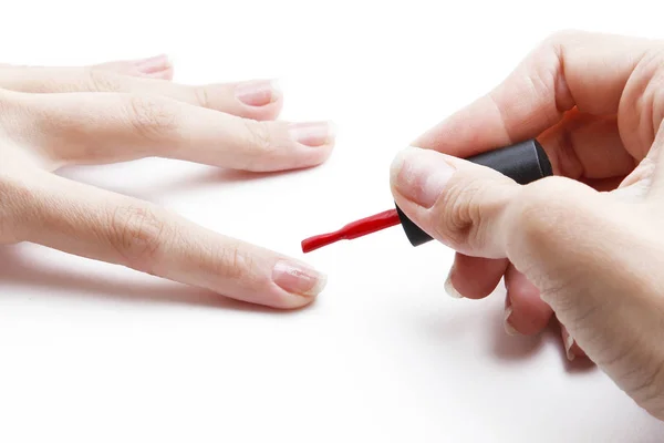 Aplicando esmalte de uñas rojo a la uña sobre un fondo blanco — Foto de Stock