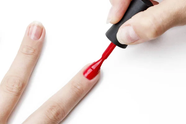Aplicando esmalte de uñas rojo a la uña sobre un fondo blanco — Foto de Stock