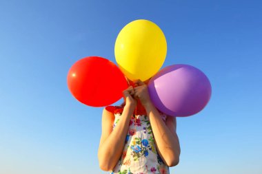 Kız yüzünü Balonlu kapsar. Utangaçlık, utanç, kızgınlık