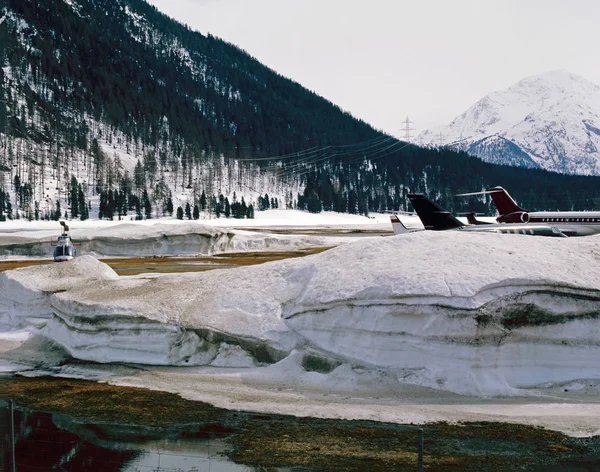 Aviones privados, aviones y un helicóptero en el paisaje cubierto de nieve de Suiza — Foto de Stock