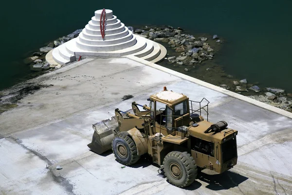 A bulldozer in making a concrete pier in the harbor of Mykonos, Greece