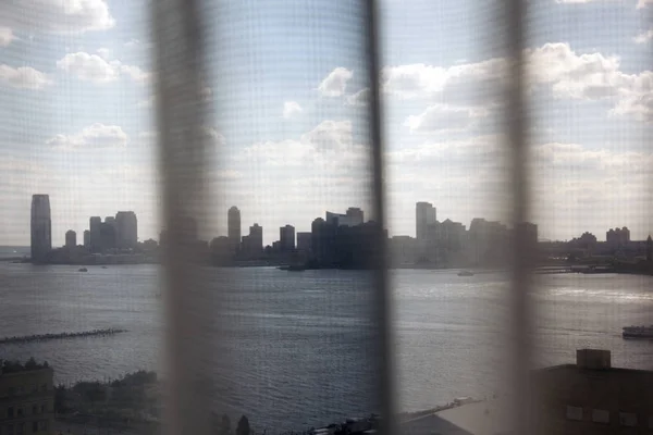A view of NYC and New Jersey skyline through a curtain