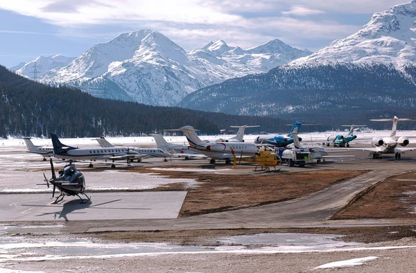 Private jets, airplanes and helicopters and a truck in the airport of St Moritz Switzerland in the scenic alps