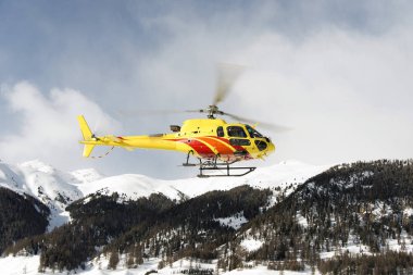 Yukarı Engadin St moritz İsviçre Alpleri'nde kış gezi için küçük bir kasaba üzerinde havada uçan bir sarı helikopter