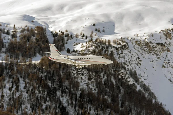 A private jet landing to St Moritz airport in snowy mountains in the alps switzerland