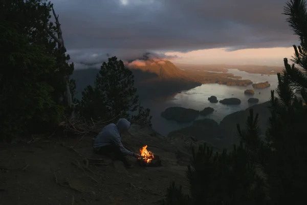 男子坐在外缘与 isl 与沿海视图上方的篝火 — 图库照片
