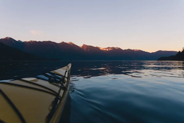 Каякинг в одиночку на спокойной воде с горами на заднем плане Wh Лицензионные Стоковые Фото