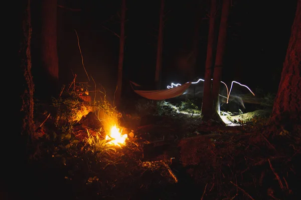 Acampar na noite na floresta com rede e fogueira — Fotografia de Stock